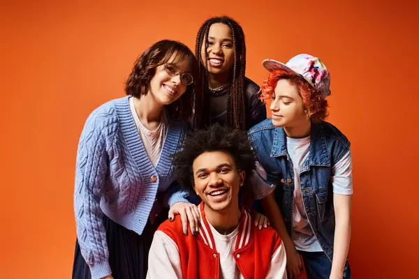 A group of young interracial friends, including a nonbinary person, standing stylishly together in a studio setting.
