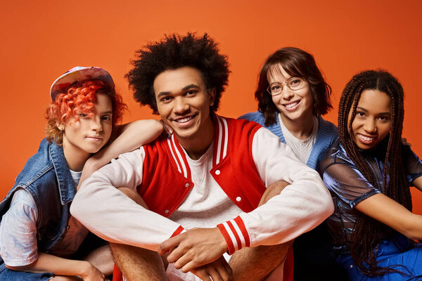 Группа молодых мультикультурных друзей, включая небинарного человека, сидящих вместе в стильной одежде в студии.