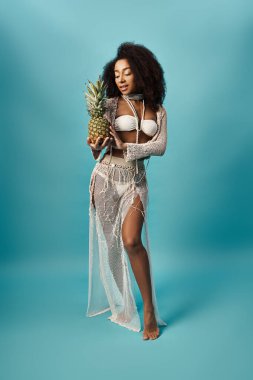 African American woman in white bikini holding pineapple. clipart
