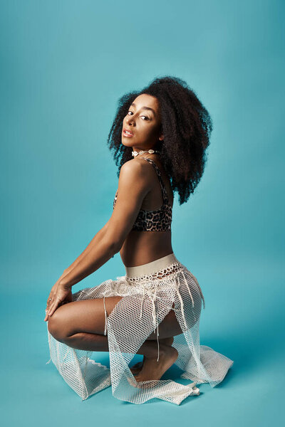 Elegant woman crouching on blue background.