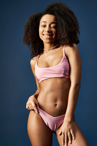 Young African American woman posing confidently in trendy pink bikini.