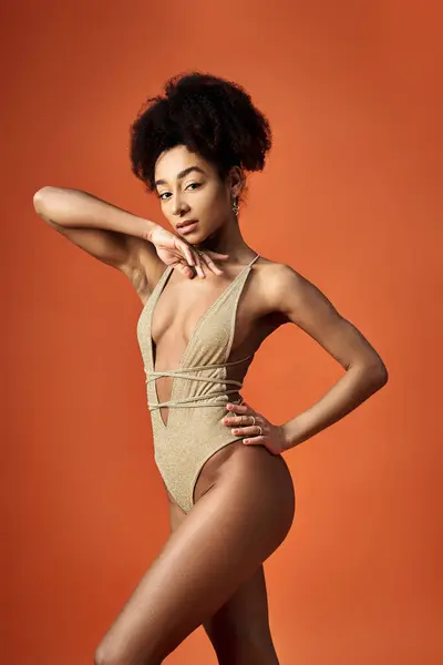 A stunning African American woman in a gold swimsuit strikes a pose.