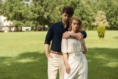 Şık giyinmiş şık bir çift. Parkta yemyeşil bir ortamda eğleniyor..