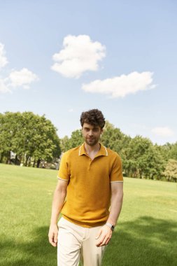 A man in a yellow polo shirt walks gracefully through a vibrant field. clipart