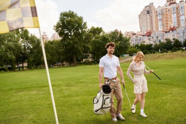 A man and woman dressed elegantly walk on a lush golf course, embodying old money style and a life of luxury. clipart