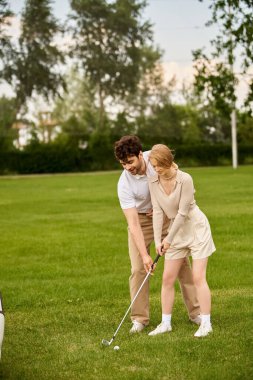 A man and woman in elegant attire play golf on a spacious green field at a prestigious country club. clipart