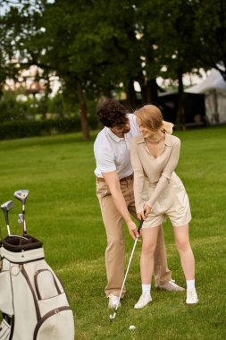 Prestijli bir golf kulübünde güneşli bir günde golf oynayan şık giyinmiş genç bir çift..