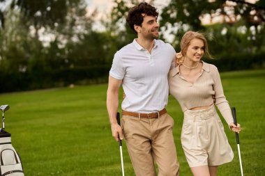 A young couple, elegantly dressed, walk on a golf course, enjoying each others company amidst lush green surroundings. clipart