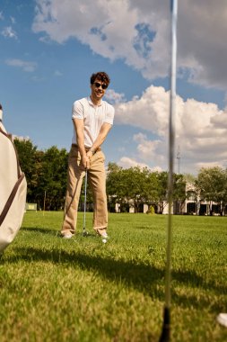 Şık, genç bir çift yemyeşil bir arazide golf oynuyor, şık giyinmiş açık havada eğleniyor..
