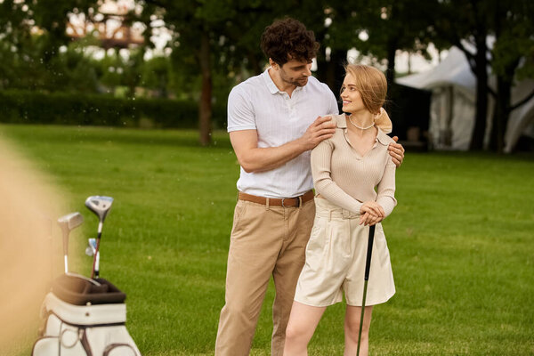 A stylish young couple in elegant attire standing side by side on a lush green golf course.