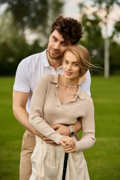 stock image A stylish couple in elegant attire strike a pose in a lush park setting, embodying a sense of sophistication and timeless beauty.