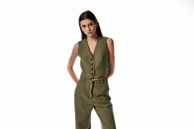 A beautiful woman with long dark hair poses in a stylish green jumpsuit against a gray backdrop, exuding elegance and sophistication. clipart