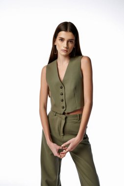 A fashionable woman with long dark hair striking a pose in a green suit against a neutral backdrop. clipart