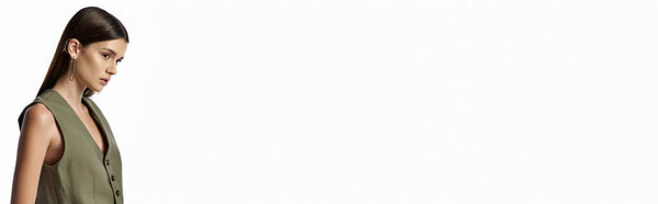 A beautiful, fashionable woman with long dark hair posing in stylish attire on a gray backdrop.