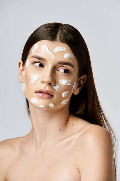 A stunning young woman wearing a white cream on her face, exuding mystery and elegance.