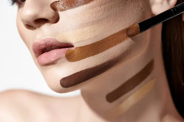 stock image Elegant young woman adorned with layers of foundation, showcasing intricate makeup artistry.