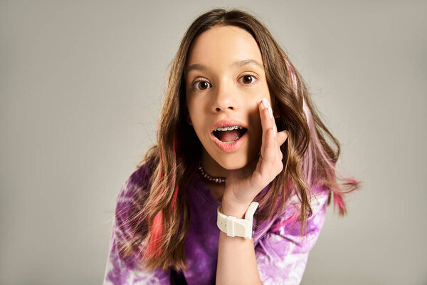 Стильная и жизнерадостная девушка-подросток, ставящая смешную позу, держащая руку лицом к лицу в забавном выражении.