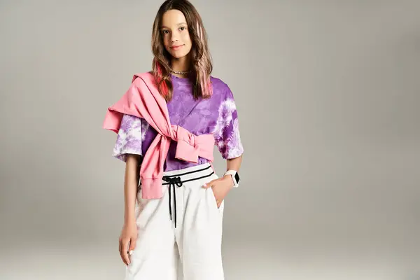 Stock image A good looking teenage girl strikes a dynamic pose in stylish attire, wearing a purple shirt and white pants.