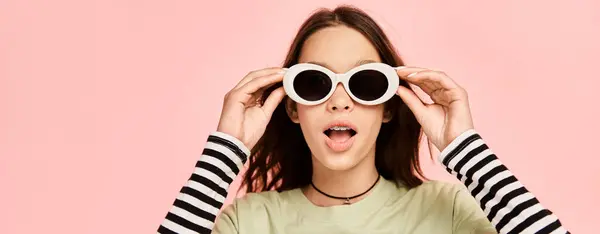 stock image A stylish teenage girl in vibrant attire playfully contorting her face while wearing sunglasses.
