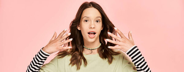 Девочка-подросток в яркой одежде с поднятыми перед лицом руками, которая принимает динамичную позу.