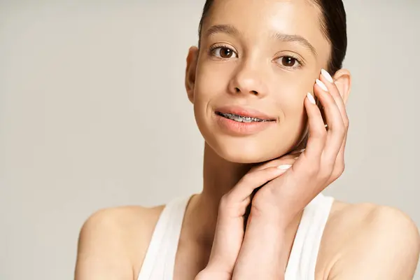 stock image A stylish teenage girl in vibrant attire poses with hands on face in an active and engaging manner.