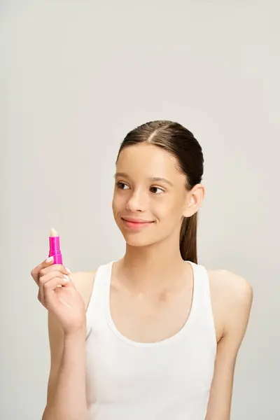 stock image Teenage girl in trendy clothes holds a pink lipstick in hand.