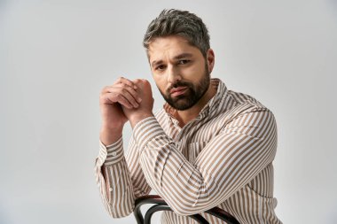 Sakallı şık bir adam sandalyeye oturur ve nazikçe elini omzuna koyar..