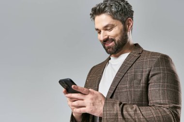 Takım elbiseli şık bir adam cep telefonuna dikkatle bakıyor, düşüncelere dalmış..
