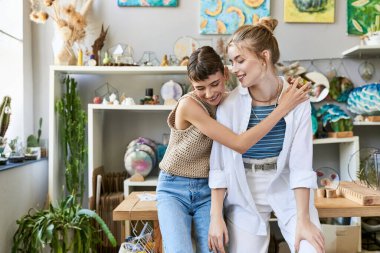 Two young women, a loving tender lesbian couple, hug in an arty room. clipart