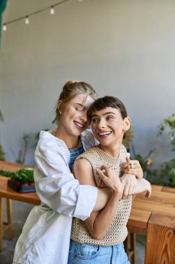 Masanın önünde kucaklaşan genç çift.