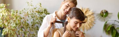 Loving lesbian couple in art studio, one woman brushing partners hair. clipart