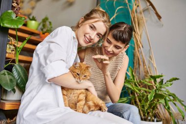 Two women sit on a bench, accompanied by a cat. clipart