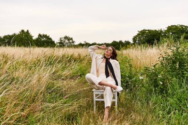 A young woman, dressed in white, sits peacefully in a chair amidst a lush field, soaking in the warmth of the summer breeze. clipart