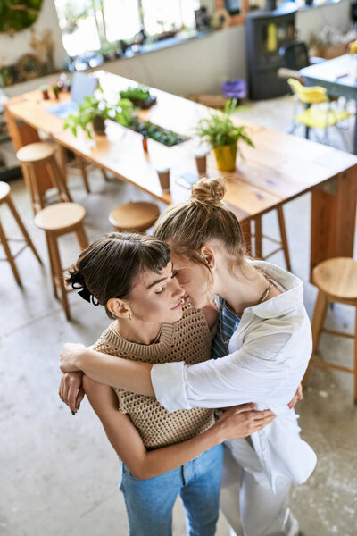 Two women share a warm embrace in a cozy restaurant setting.