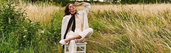 一位身穿白衣的年轻女子平静地坐在一片茂密的田野里的椅子上 拥抱着夏日的微风 — 图库照片