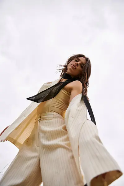 stock image A young woman in a white dress and black scarf gracefully dances in a sunlit field, enjoying the summer breeze.