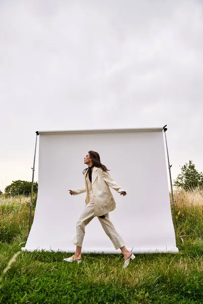 一位身穿白衣的年轻漂亮女子平静地站在阳光普照的田野里 享受夏日的微风 — 图库照片