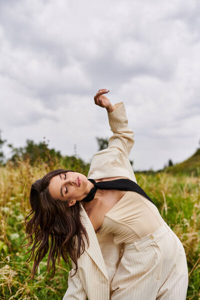 A beautiful young woman in a white suit and black tie enjoying the summer breeze in a field.