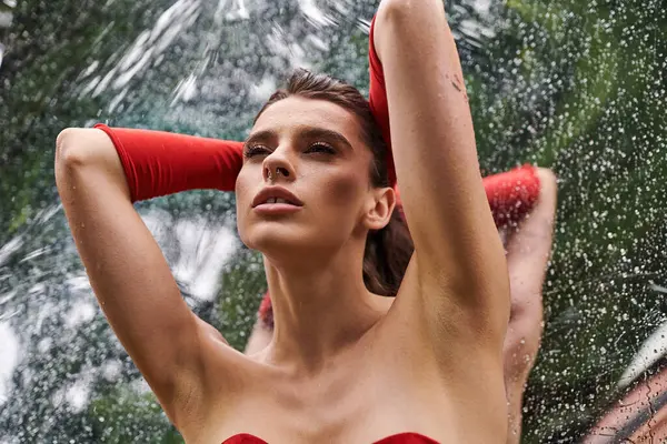 Stock image A stylish young woman in a vibrant red gloves stands gracefully in the tranquil water, enjoying a leisurely summer day.