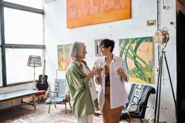 Olgun lezbiyen çift sanat stüdyosunda duruyor..