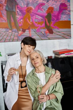 İki sofistike kadın omuz omuza, ellerinde şarap kadehleriyle.