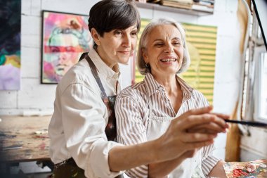 Two women painting together in an art studio. clipart