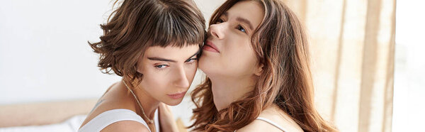 A beautiful lesbian couple in comfy attire, looking deeply into each others eyes.