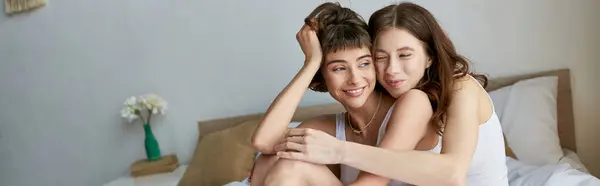 stock image A beautiful lesbian couple in comfy attire enjoying a cozy moment on a bed.