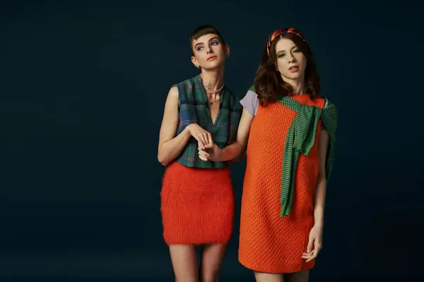 Two women in dresses standing side by side.