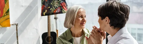 stock image Two mature women stand elegantly together in an art studio.