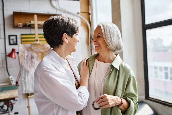 Две женщины стоят вместе перед окном.