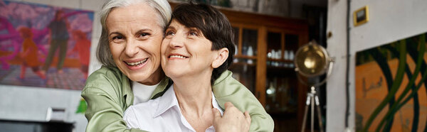 Веселая женщина обнимает брюнетку в теплой обстановке.