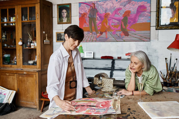 Two woman admire a painting in an art studio.