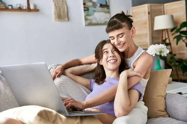 Lesbian Couple Comfy Attire Sitting Couch Using Laptop lizenzfreie Stockfotos